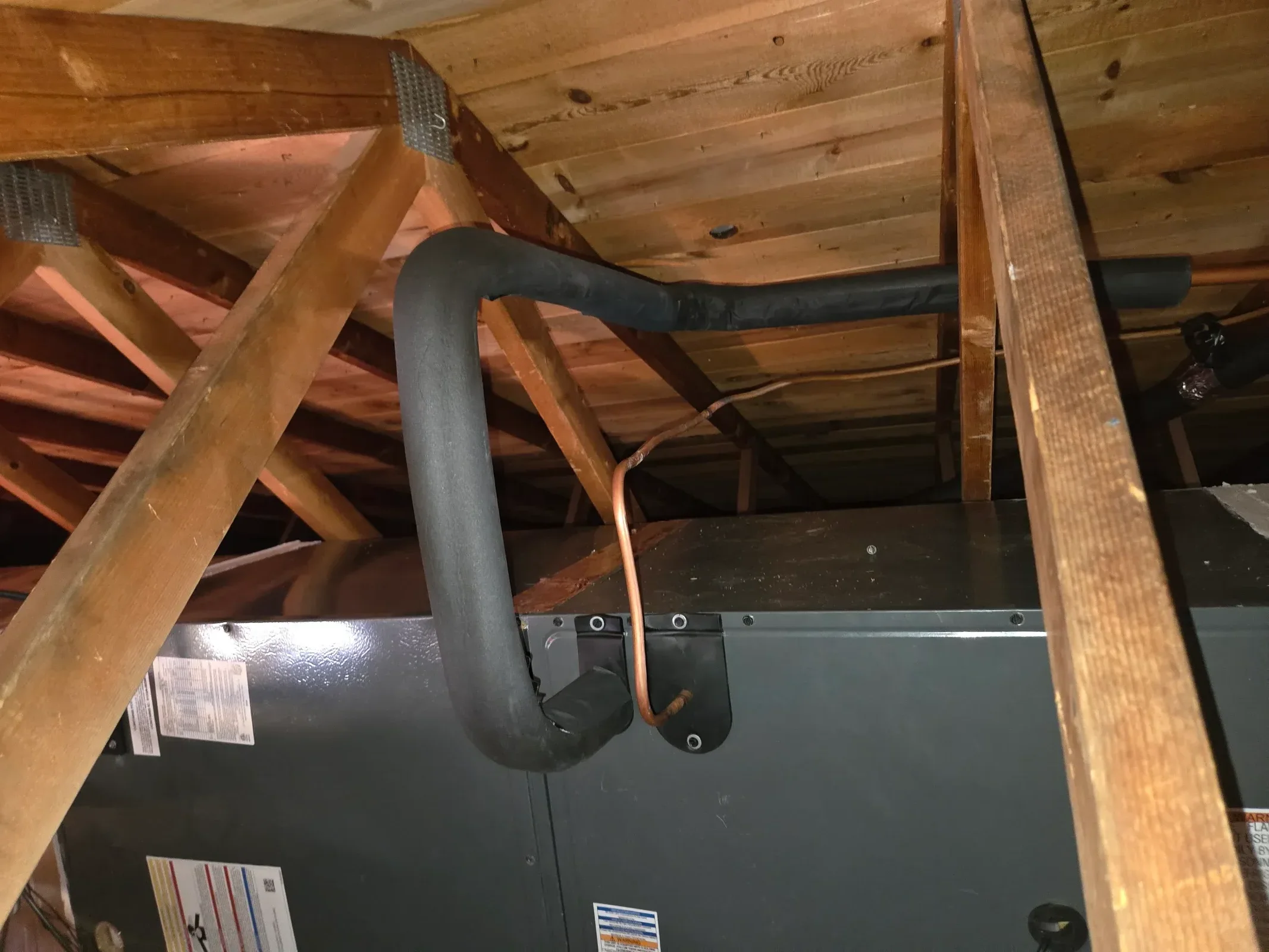 Sheet metal ductwork with copper piping and black flex ducting installed in commercial HVAC system